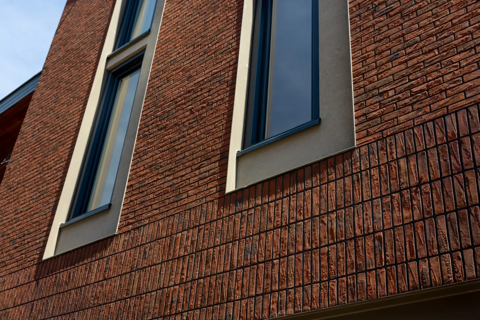 Geveldetail met verticaal metselwerk en donkere kozijnen bij revitalisering in Oldenzaal, door LEF Architecten.