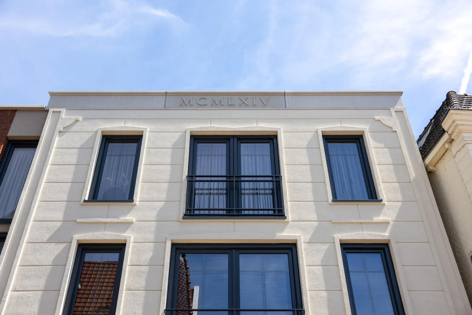 Historische witte gevel met vernieuwde kozijnen in het centrum van Oldenzaal, door LEF Architecten.